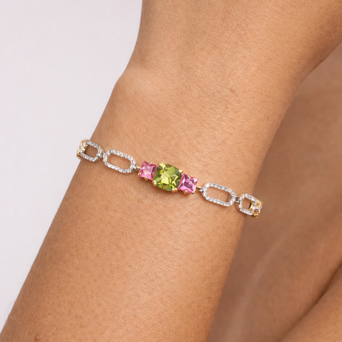 Happiness peridot, pink sapphire and diamond link bracelet in 18K gold, worn on the wrist