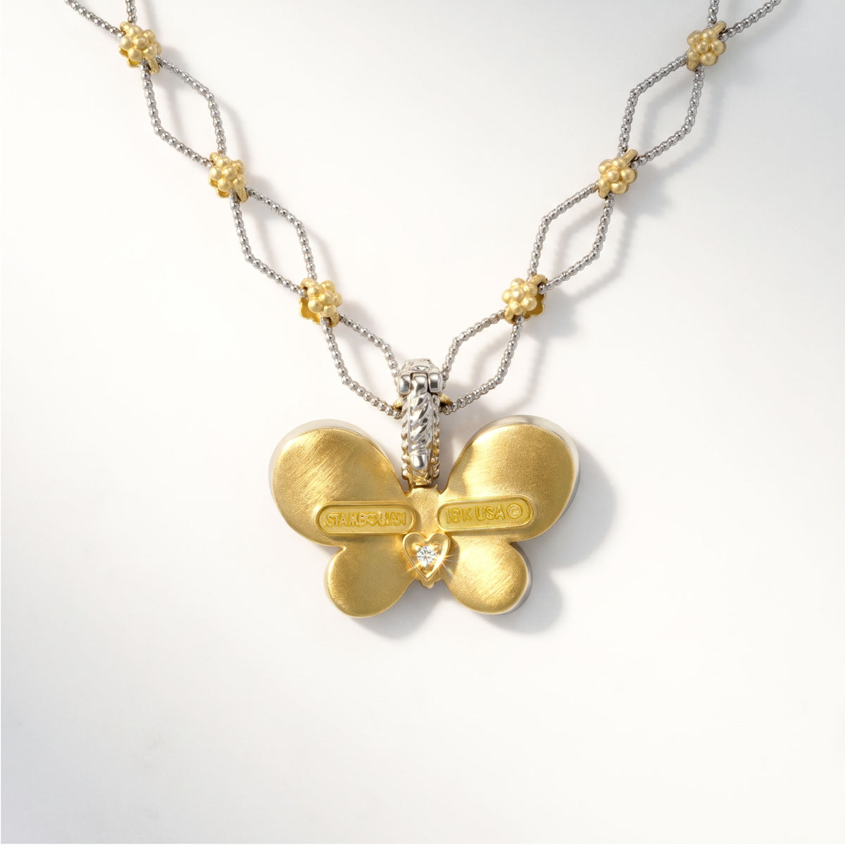 Large butterfly enhancer pendant in 18K two-tone gold with diamonds, back view showing the signature diamond heart