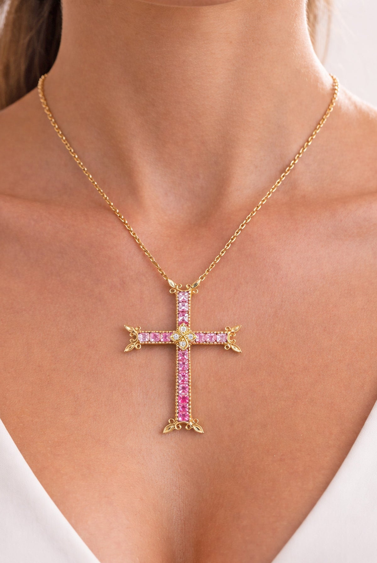 18K gold cross pendant with princess cut pink sapphires and diamonds, worn on a model