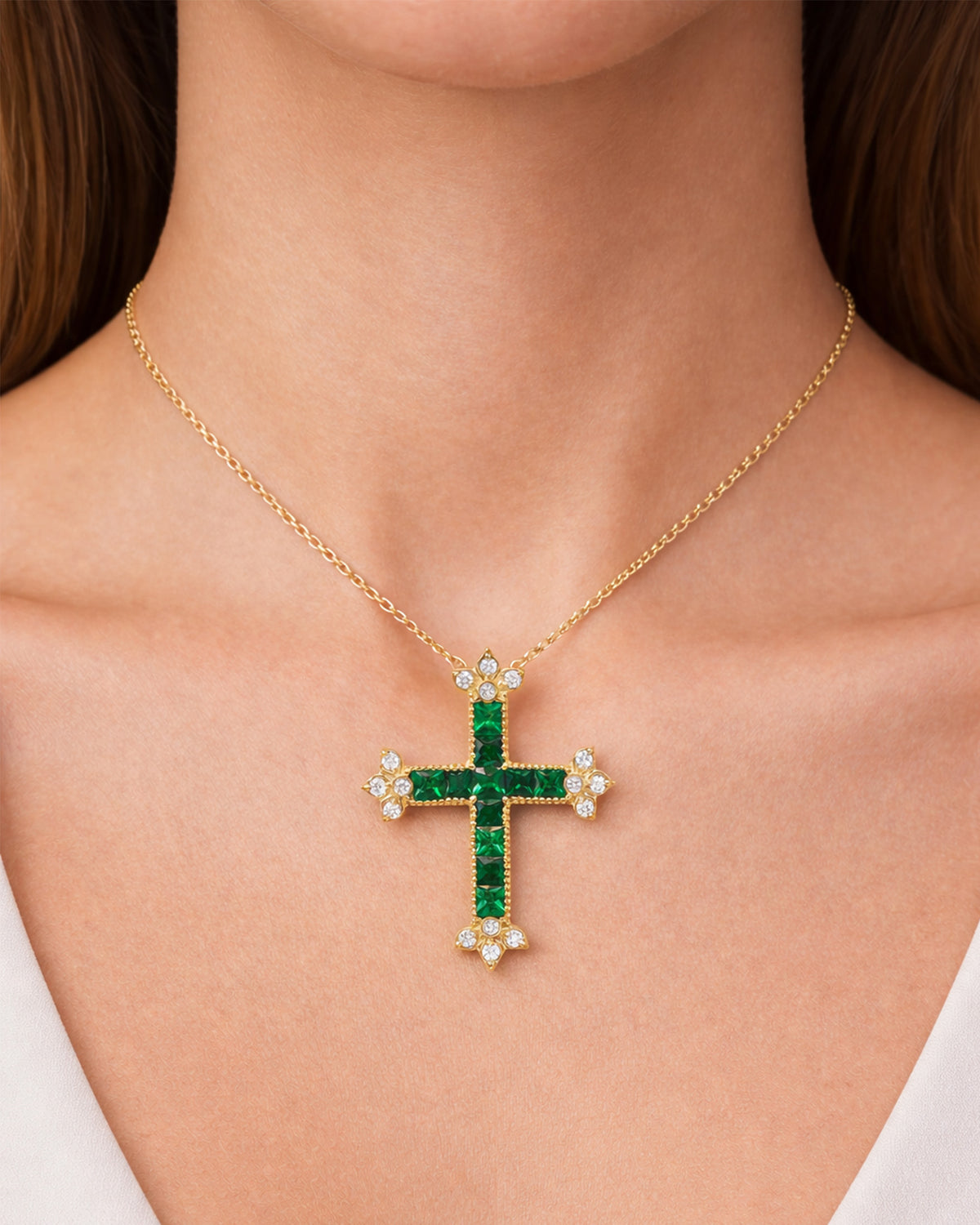 Princess-cut tsavorite garnet and diamond cross pendant in 18K yellow gold, worn on a model