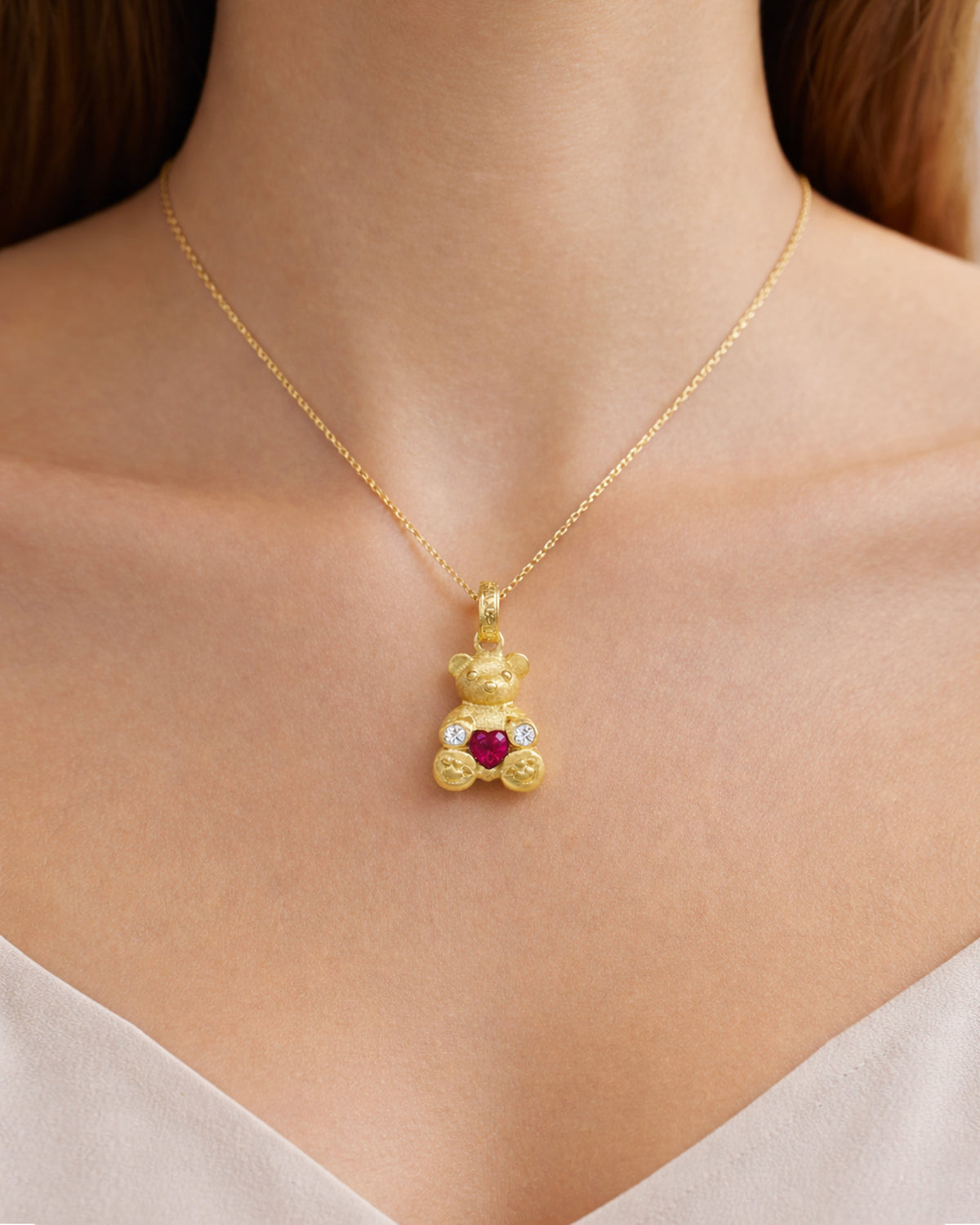 Teddy Bear 18K gold charm pendant with heart shape ruby and diamonds, worn on a model