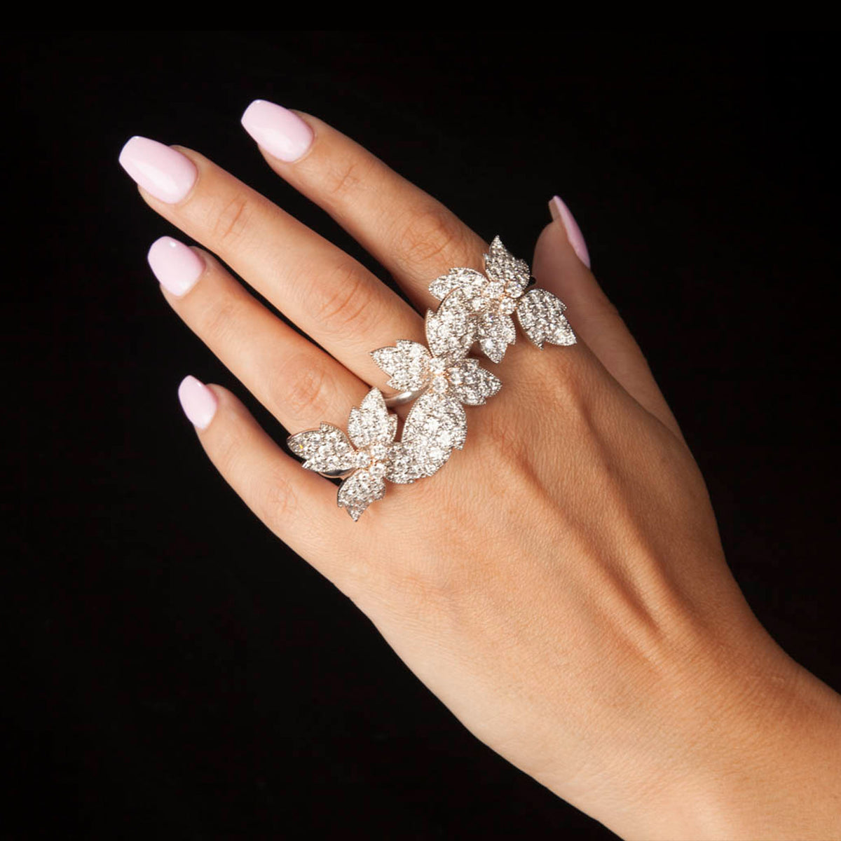 18K white and pink gold three-finger floral diamond ring, worn on the hand