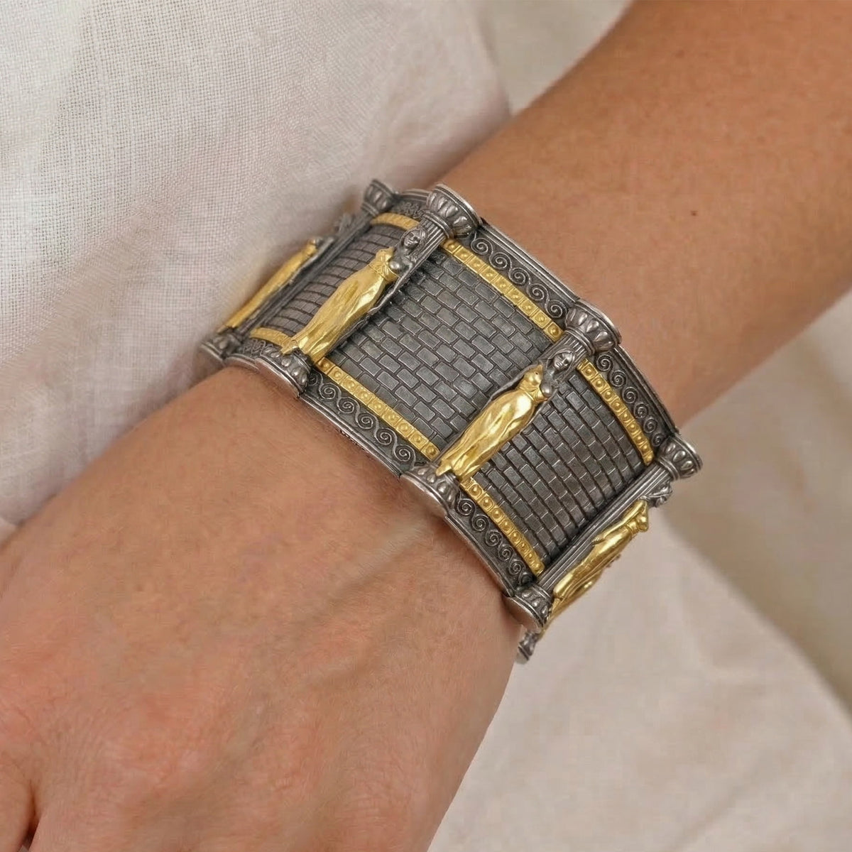 "Acropolis" aged silver and 18K gold bracelet with gold caryatid figures, worn on the wrist
