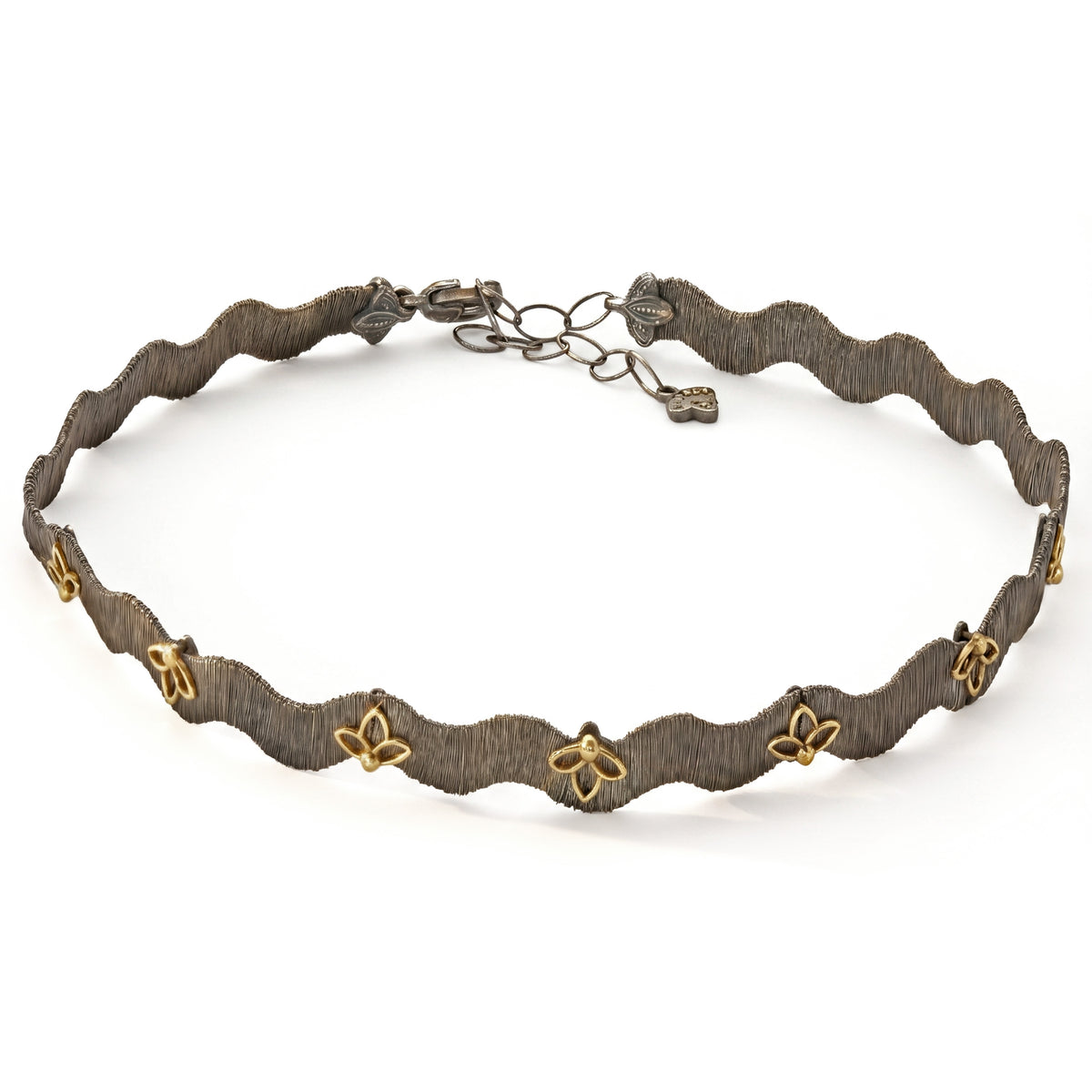 Floral choker necklace in aged silver and 18K gold, wavy band with gold flower accents, top-down view